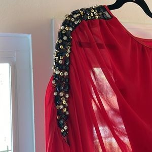 Red one shouldered mini with black and gold embellishment on the left shoulder